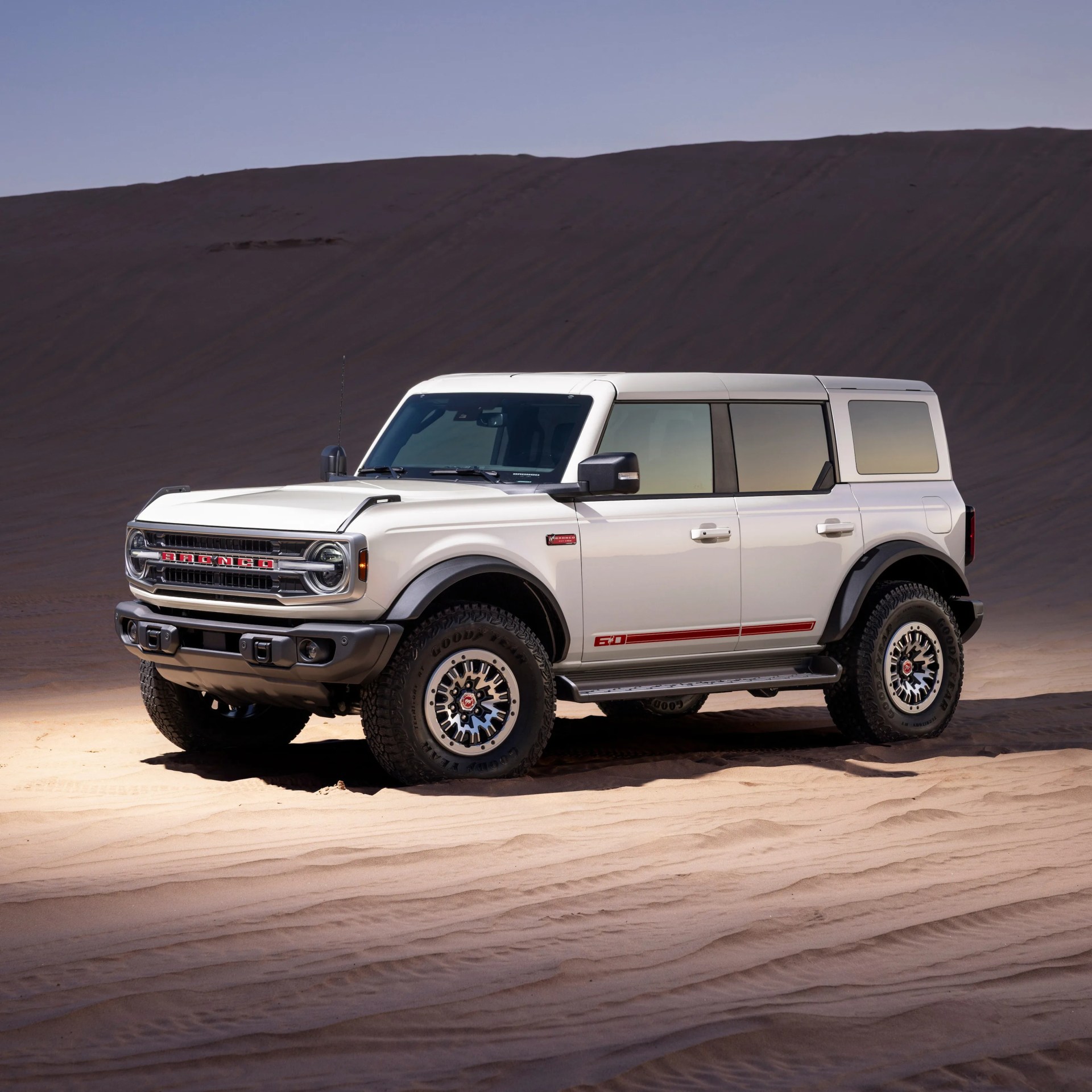 a front 3/4 shot of a white ford bronco suv on a sandy backdrop