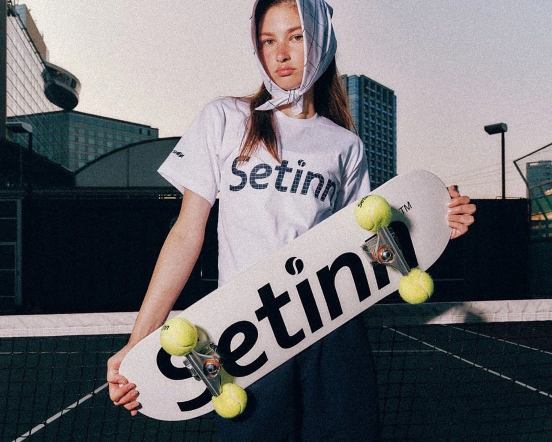 model wearing Vans x Setinn Capsule Collection on tennis court and holding skateboard