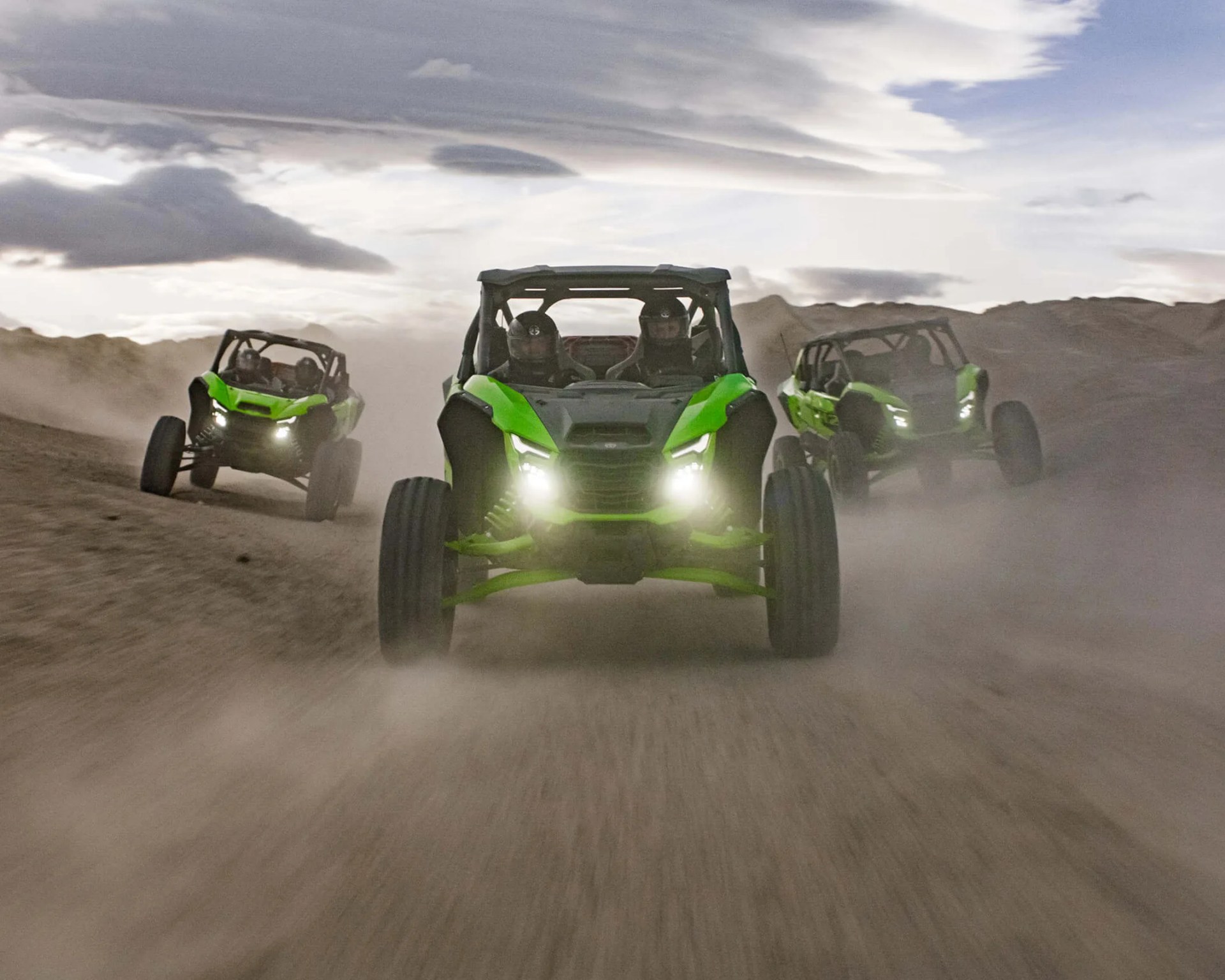 a photo of three kawasaki utvs driving head-on