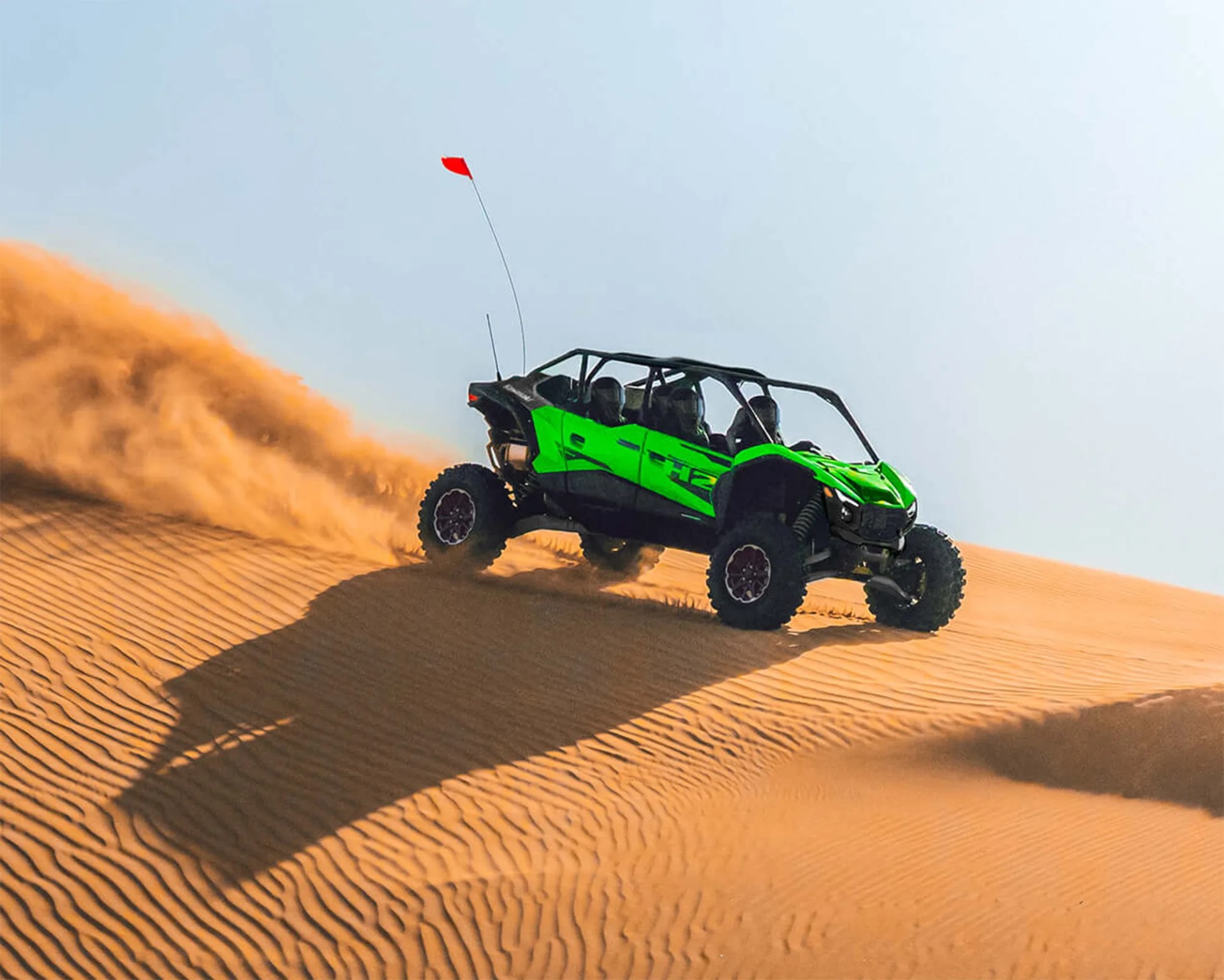 a photo of a kawasaki side-by-side driving on sand dunes