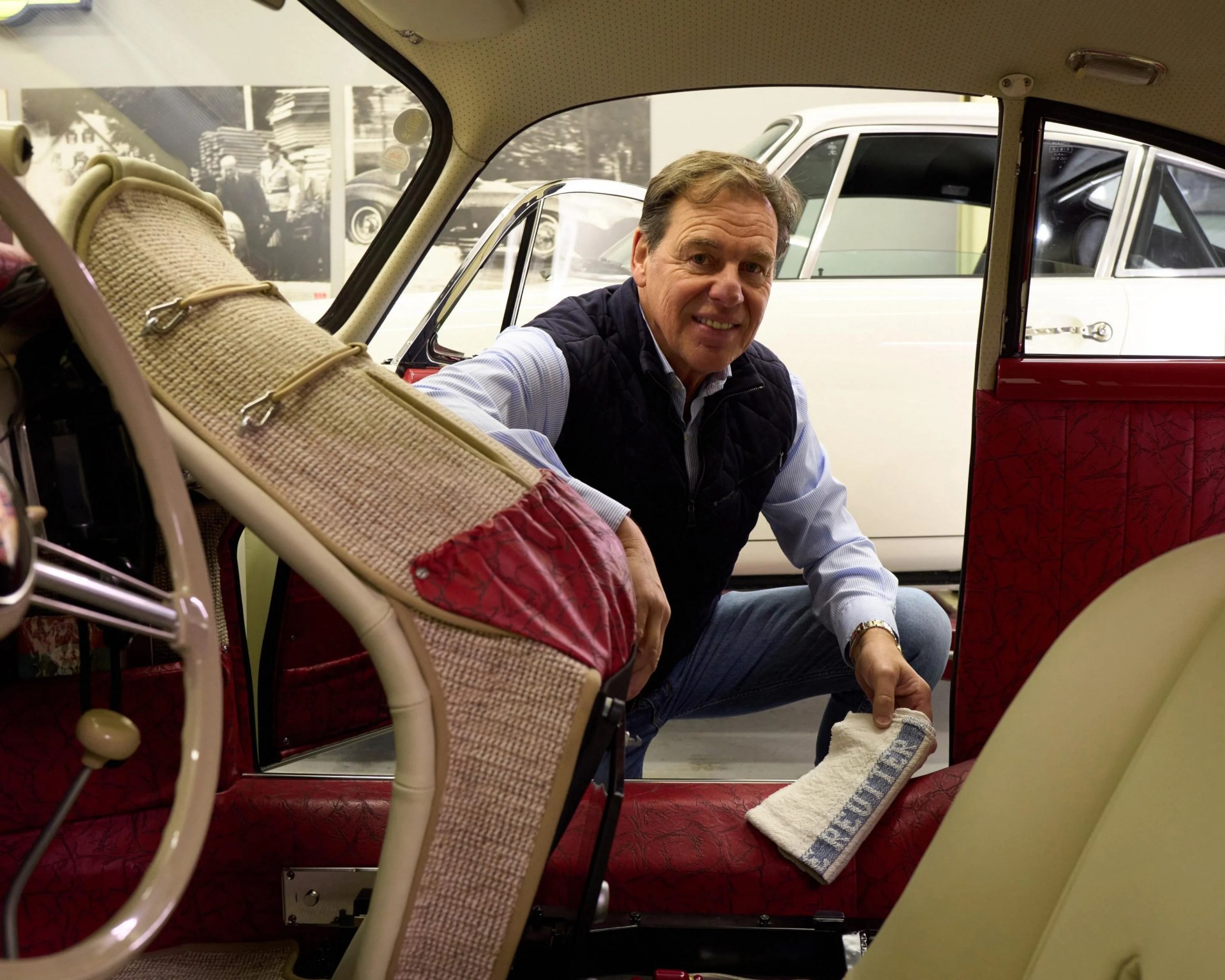 a photo of a man leaning into the interior of a classic porsche sports car